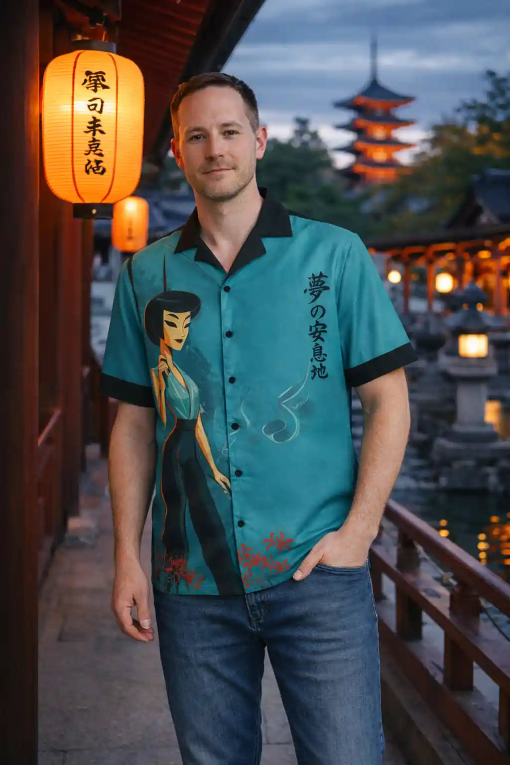 Man wearing a teal shirt with anime design in an outdoor setting with lanterns and traditional architecture.