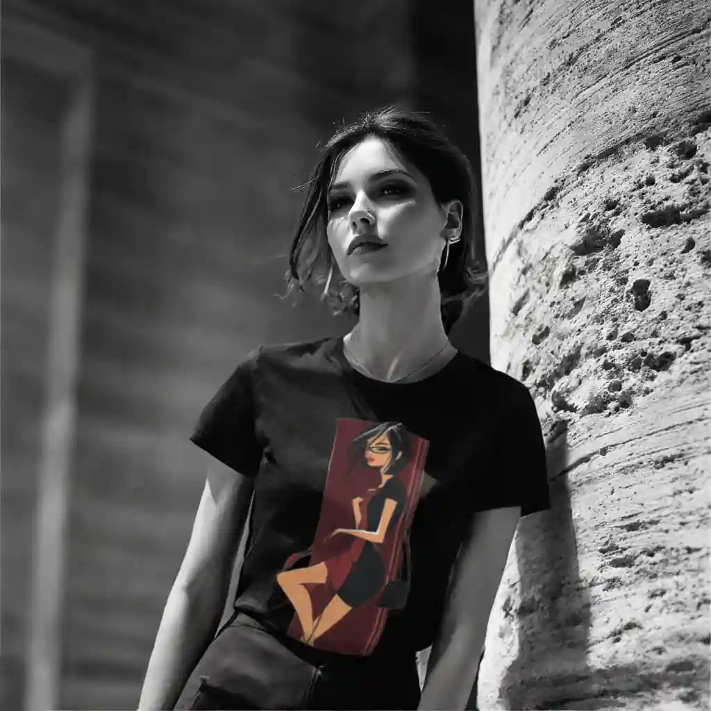 Model wearing a black t-shirt with a rectangular art print of a stylized woman in a red dress against a red background. Black and white urban background with color splash effect on the shirt art. Highlights wearable art lifestyle.