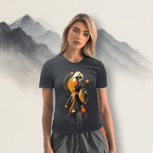 Female model wearing a dark grey t-shirt with a stylized figure and abstract print in orange, black, and white, standing against an artistic mountain backdrop. Shows the t-shirt's fit and lifestyle context as wearable art.