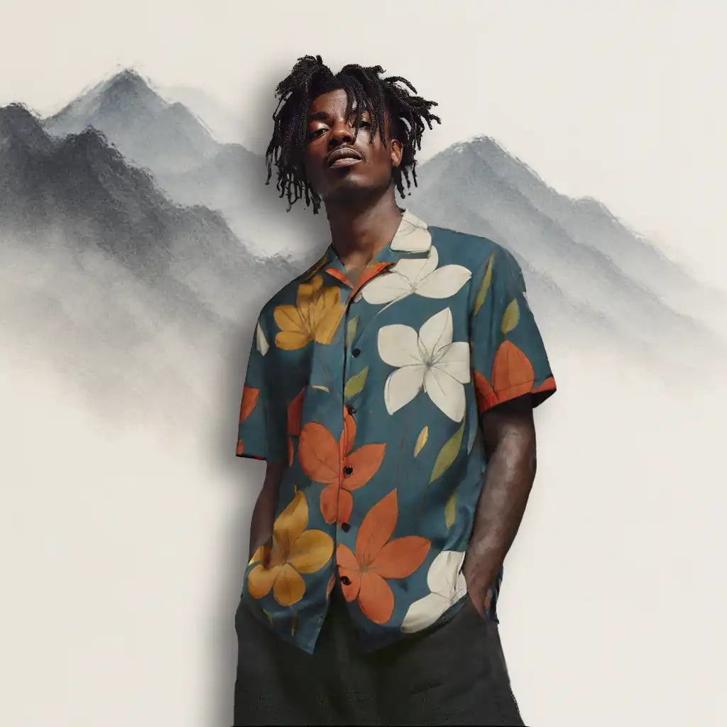 Male model wearing a teal button-up shirt with a large orange and white floral print, standing against an artistic mountain background. Shows the shirt's fit and lifestyle context as wearable art.