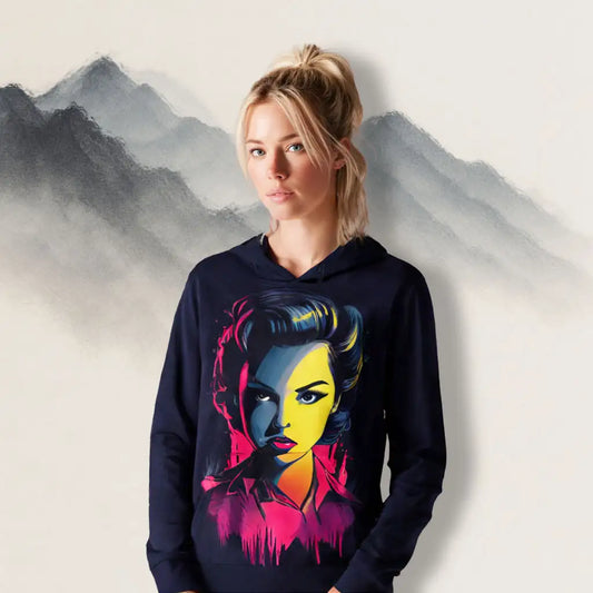 A woman wearing the Neon Femme Portrait Hoodie in front of misty watercolor mountains, highlighting the vibrant pop-art face design.