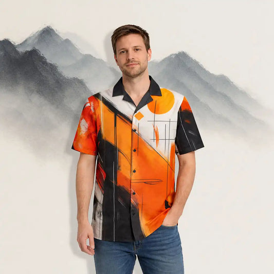 A man wearing a short-sleeve button-up shirt featuring a bold abstract design in orange, black, and white, standing in front of a soft, painted mountain backdrop.