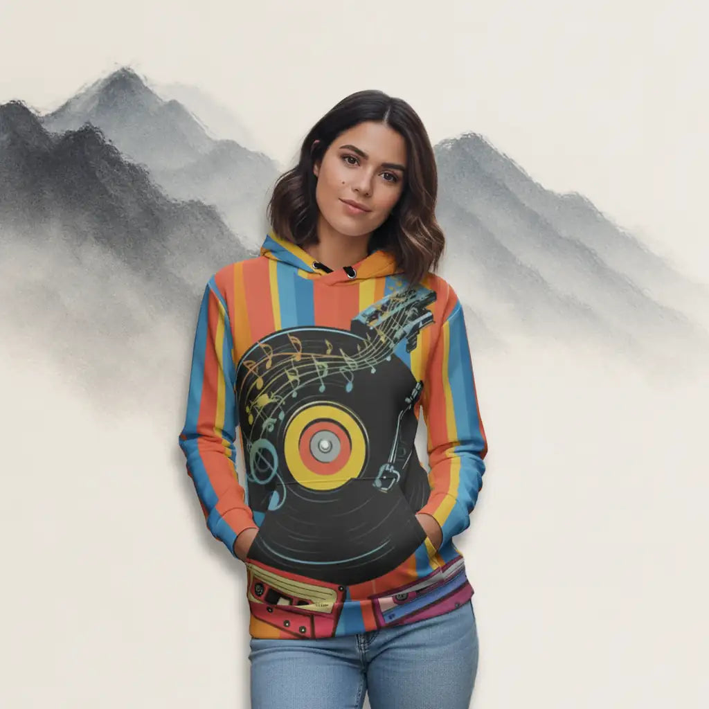 Young woman with dark hair wearing the retro music themed hoodie and jeans, standing with hands in pockets against a stylized mountain background in a studio setting.